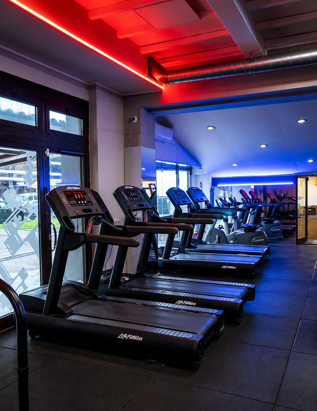 La zona cardio di Nonsolofitness Torvaianica con tapis roulant e neon rossi e blu