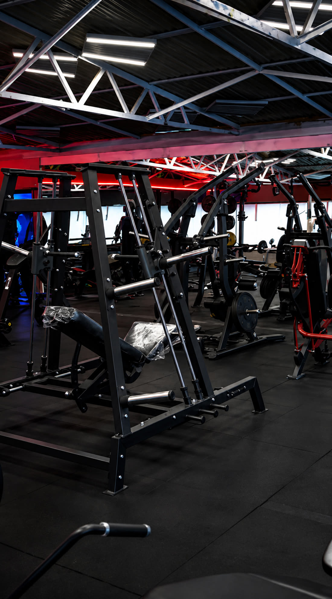 La sala macchine di Nonsolofitness Torvaianica con panche e attrezzi sotto il soffitto industriale